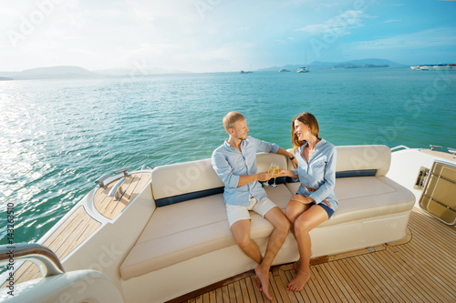 Romantic vacation and luxury travel. Young loving couple sitting on the sofa on the modern yacht deck. Sailing the sea. © luengo_ua