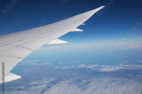 Aircraft wing over clouds, flying background clouds over USA