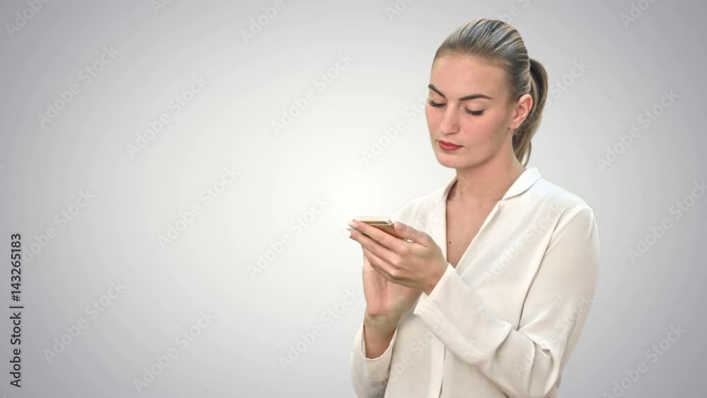 Pensive business woman using mobile cell phone reading message, wear white suit on white background. Pensive business woman using mobile cell phone reading message, wear white suit on white background.