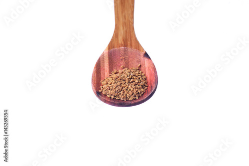 Fenugreek seeds on a brass spoon isolated on a white background. photo