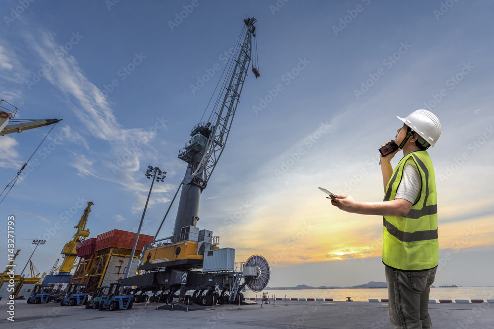 foreman take command safety instruction to the workers in terminal yard of port at sunset in background