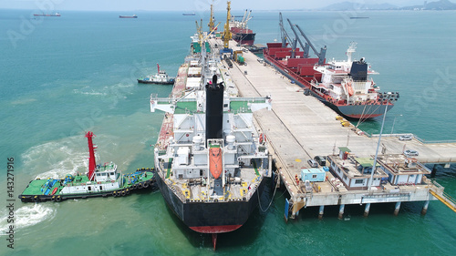 ship ocean vessel in berhing along side the jetty terminal of port pushing by the tug boats in safety cirscumstance