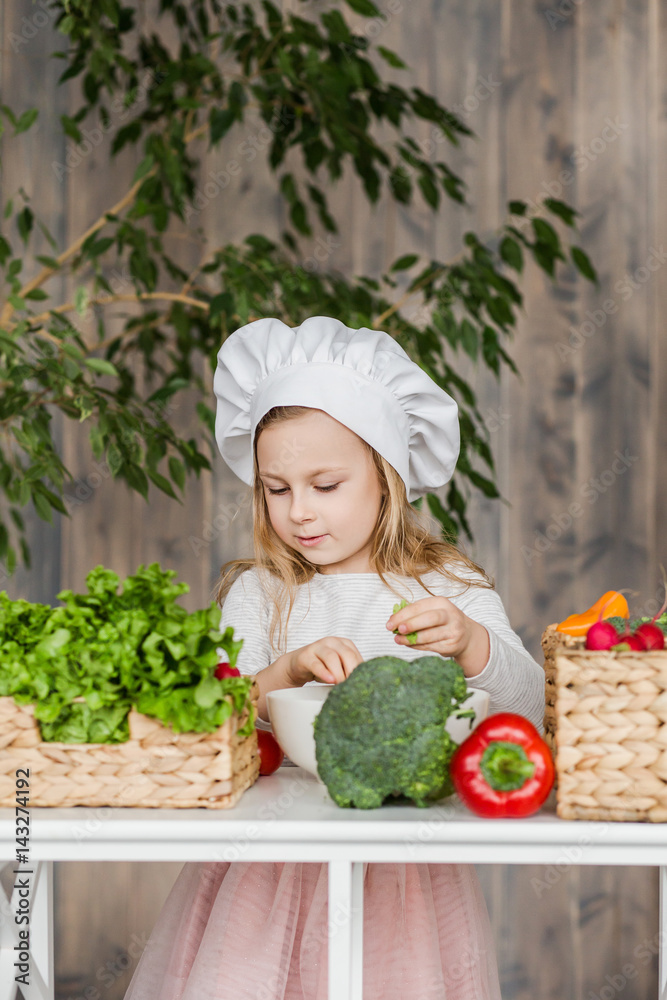 Little beautiful girl making vegetable salad in the kitchen. Healthy food. Little housewife Little beautiful girl making vegetable salad in the kitchen. Healthy food. Little housewife