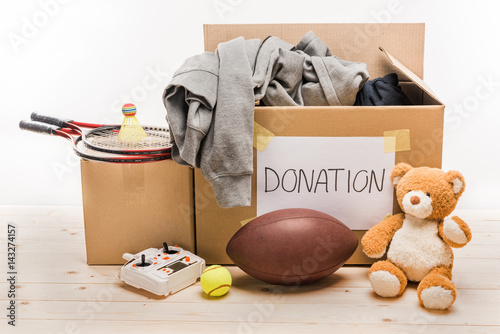 cardboard boxes with donation clothes and different objects on white, donation concept photo