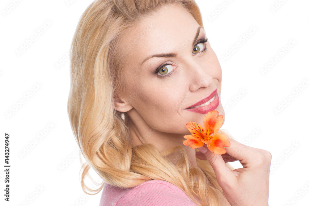 Touched by nature. Closeup portrait of a beautiful woman smiling to the camera holding a flower to her face isolated on white