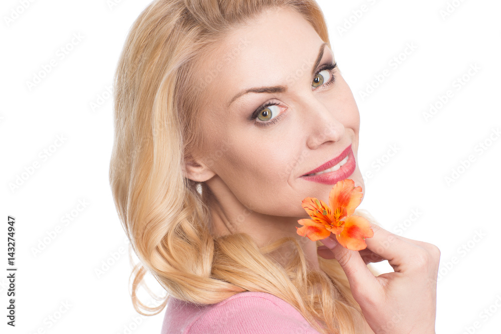 Touched by nature. Closeup portrait of a beautiful woman smiling to the camera holding a flower to her face isolated on white Touched by nature. Closeup portrait of a beautiful woman smiling to the camera holding a flower to her face isolated on white