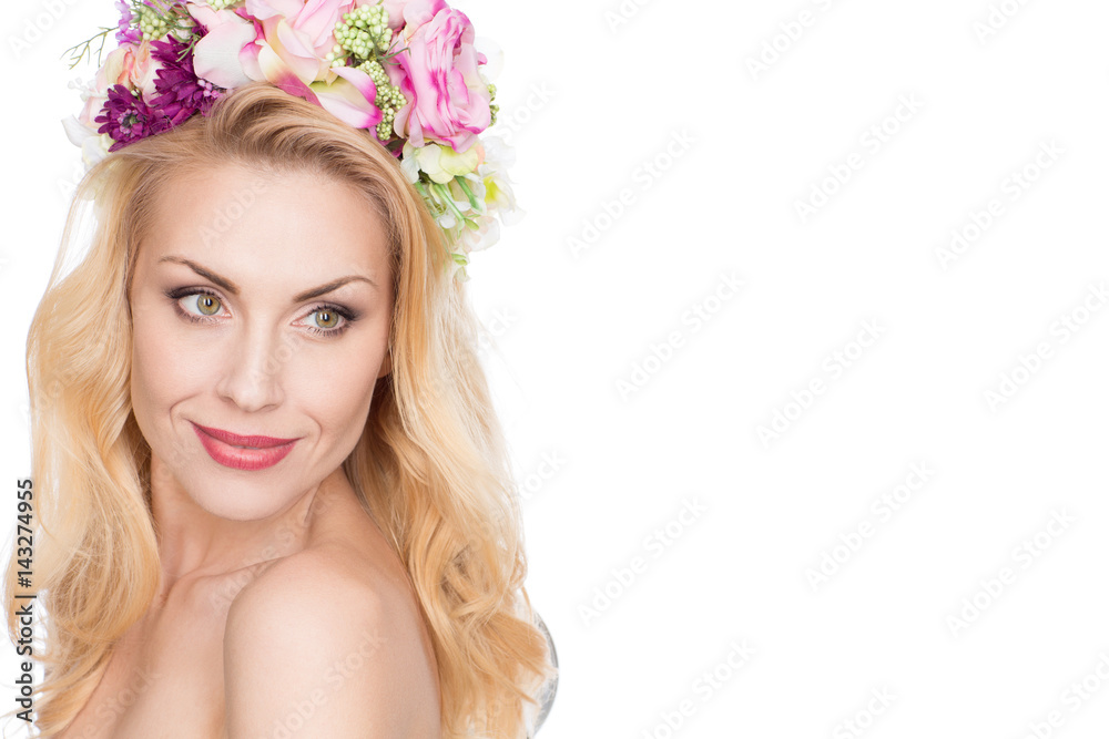 Floral queen. Studio portrait of a gorgeous mature woman wearing flowers headpiece looking over the shoulder smiling isolated on white