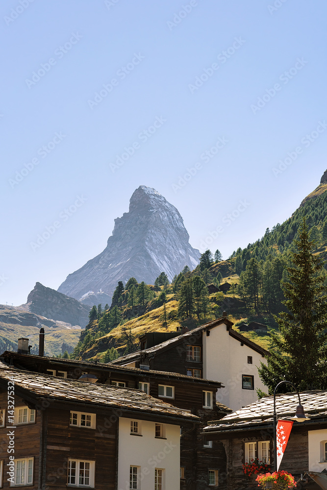 Traditional Swiss Chalets in Zermatt with Matterhorn peak with flag