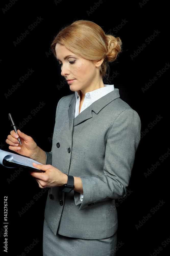 Beautiful blonde businesswoman holding folder with papers and pen on black Beautiful blonde businesswoman holding folder with papers and pen on black