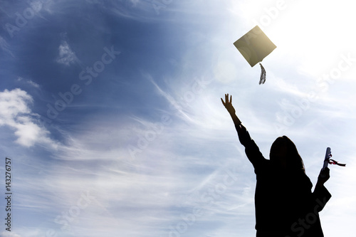 Graduate students tossing up hats over blue sky