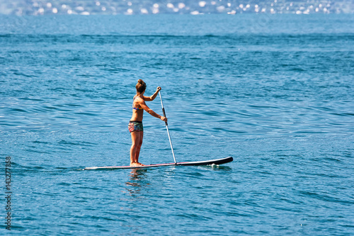 Girl standing on standup paddle surfing in Geneva Lake Montreux in Switzerland © Roman Babakin