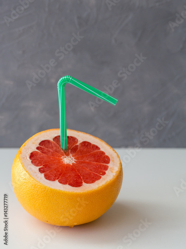 grapefruit in the form of a cocktail with a straw