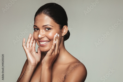 Smiling female model applying moisturizer photo