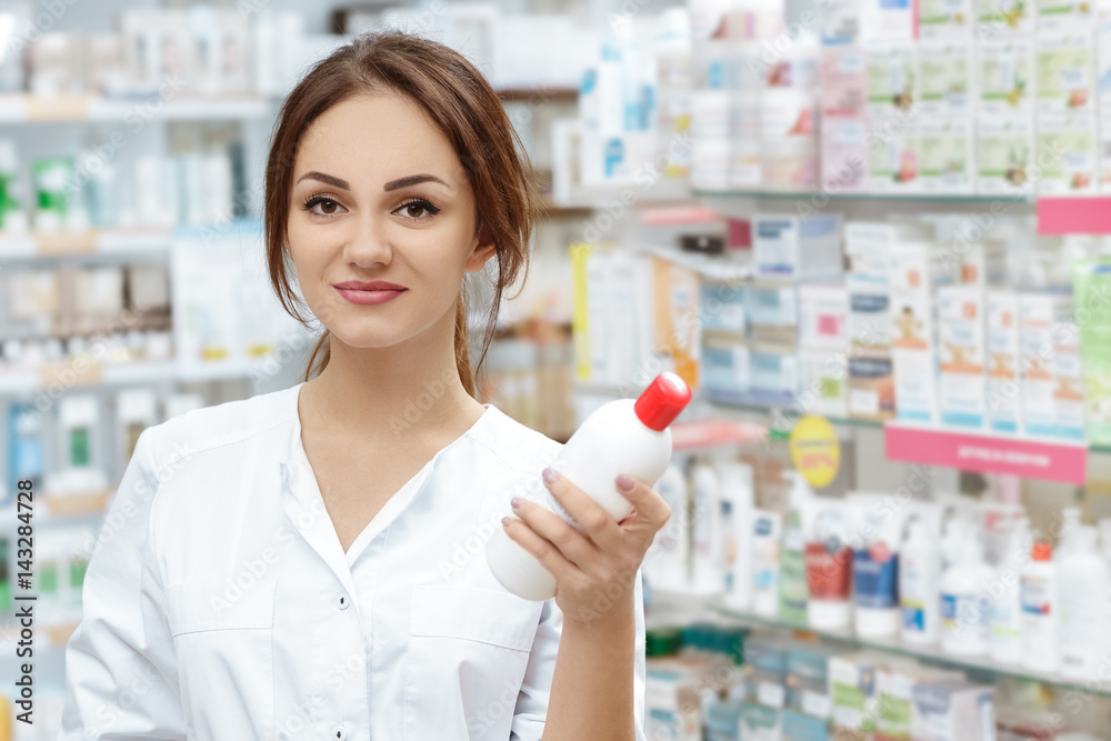 Professionalism is her main focus. Portrait of an attractive pharmacist offering holding medical shampoo looking to the camera smiling.