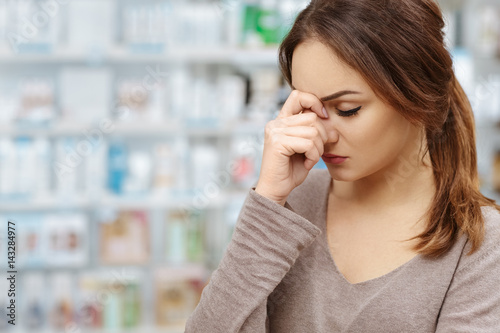 Feeling bad. Shot of a young woman having headache touching her forehead at the local drugstore.