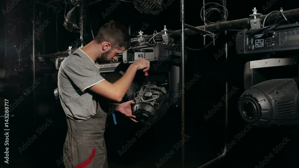 The lighting engineer repairs the light device on stage