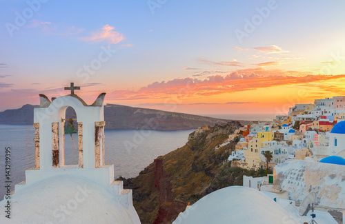 cityscape of Oia, traditional greek village of Santorini, with white bellfry at sunset, Greece