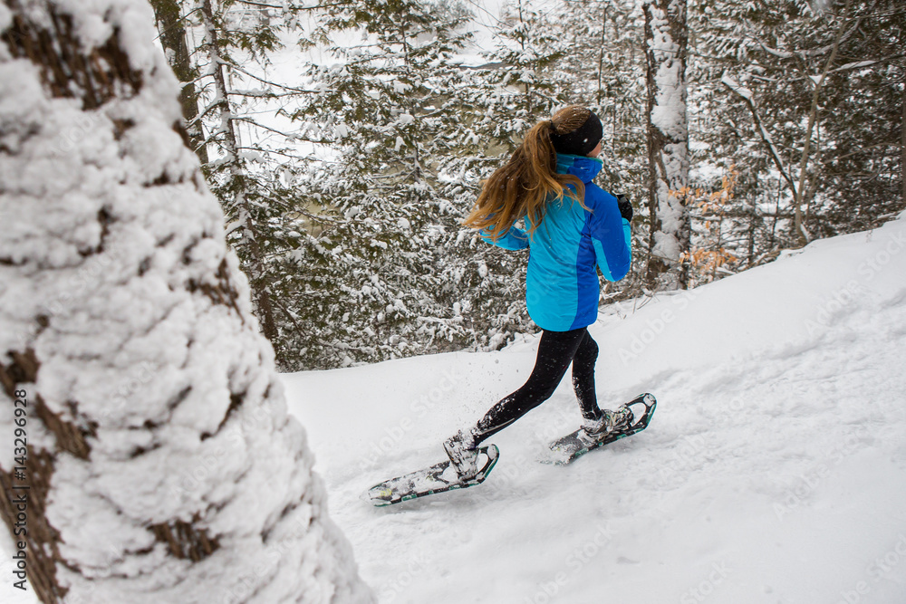 Lone woman running in the forest on snowshoes