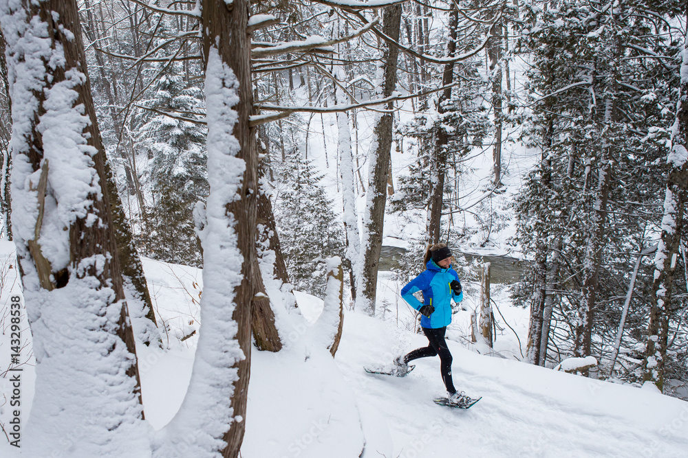 Lone woman running in the forest on snowshoes