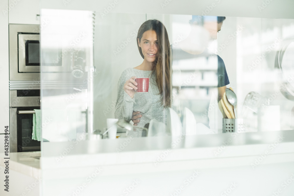 Portrait of young woman holding coffee cup with boyfriend in modern kitchen Portrait of young woman holding coffee cup with boyfriend in modern kitchen