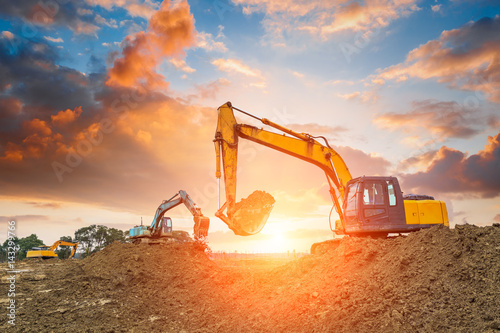 Photo excavator in construction site on sunset sky background