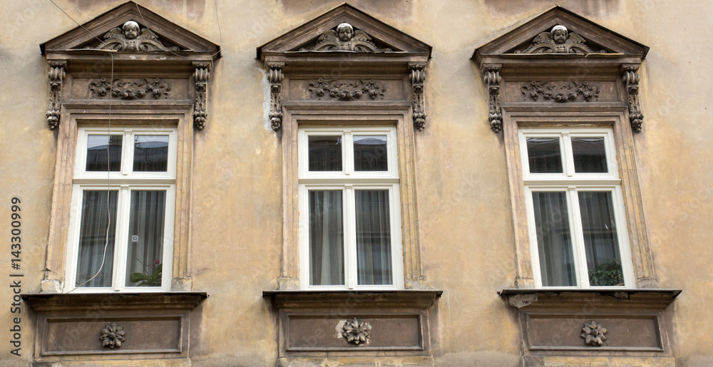 Three vintage design windows on the facade of the old house
