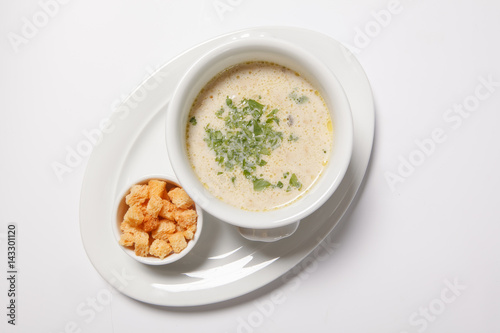 delicious creamy soup with croutons and greens on white dish