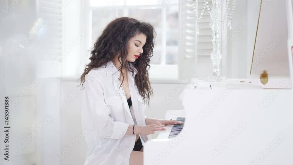 Couple in elegant apartment, woman playing piano in just lingerie & shirt Couple in elegant apartment, woman playing piano in just lingerie & shirt