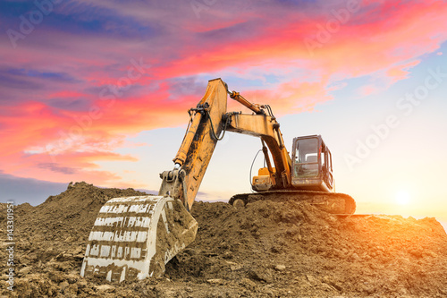 excavator in construction site on sunset sky background photo