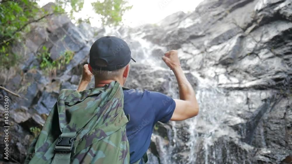 Young Man Open Arms to Amazing Jungle Waterfall Expressing Happiness and Freedom. Beautiful Thailand Nature. Young Man Open Arms to Amazing Jungle Waterfall Expressing Happiness and Freedom. Beautiful Thailand Nature.