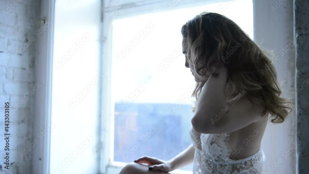 Model poses before camera in lace underwear inside studio. Sensual, beautiful and attractive young blonde woman, with long wavy blond hair, slim seductive figure and pretty face, with large bust size