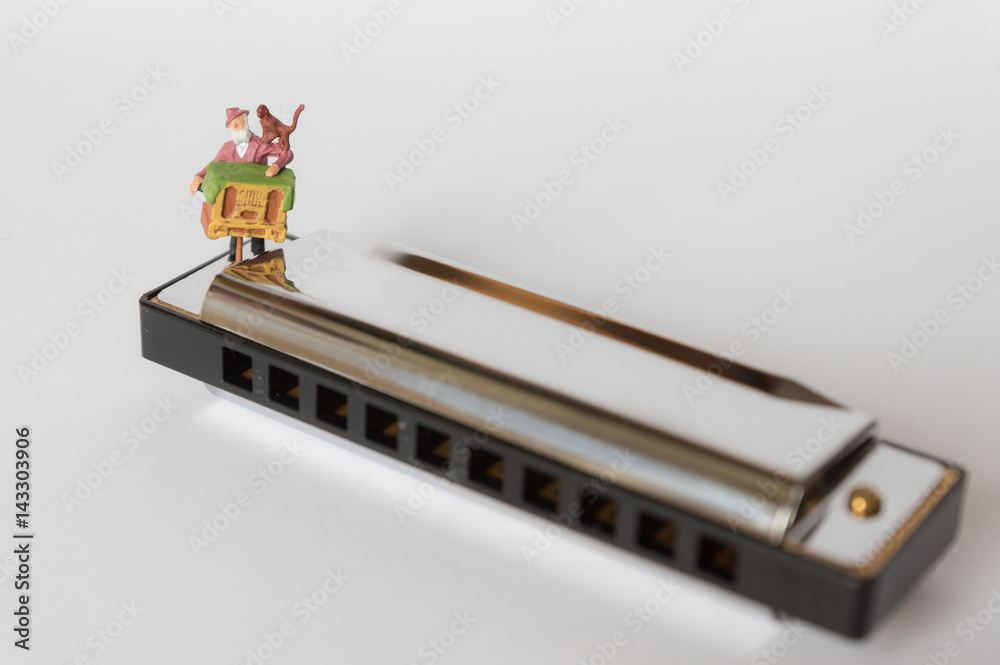 Miniatur Drehorgelmann spielt auf einer Mundharmonika
