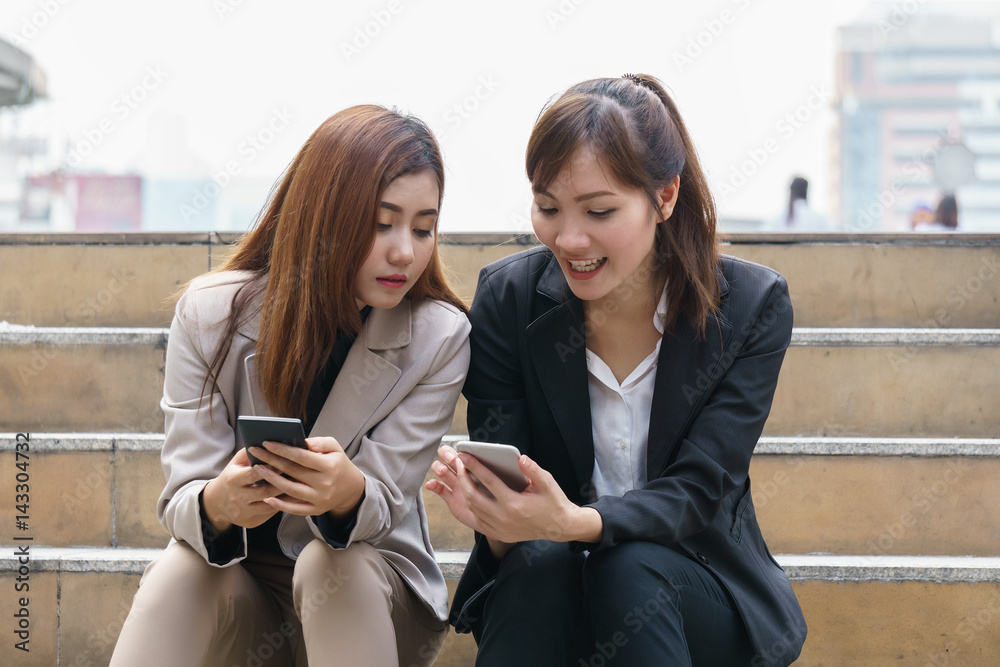 Two smiling girls watching something in smartphone Two smiling girls watching something in smartphone