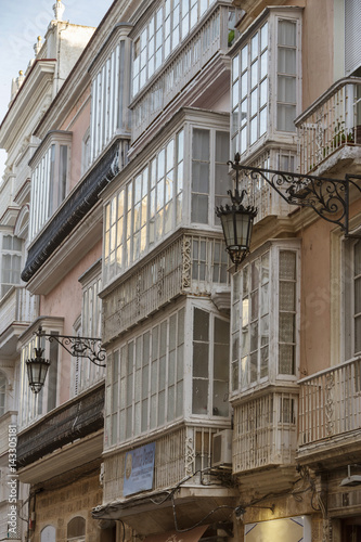Detail of balconies and large windows on the time of the nineteenth century, Narrow street with traditional architecture in Cadiz, Andalusia, southern Spain