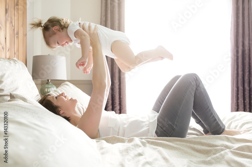 Young happy mother with baby on bed