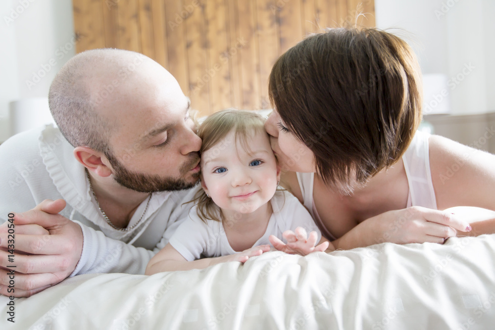 Family with child. Happy parents playing with baby on bed Family with child. Happy parents playing with baby on bed