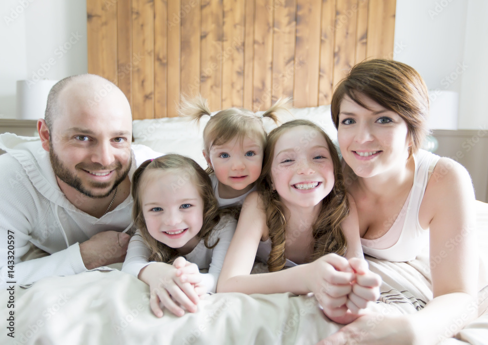 Young happy family of five on bedroom