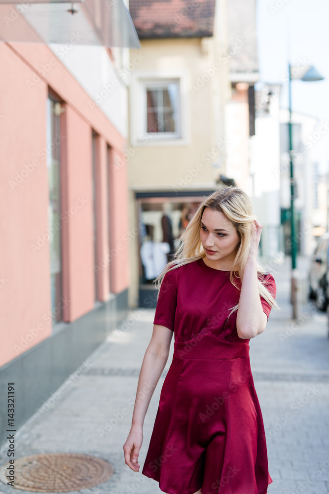 Blonde Frau in rotem Kleid geht in Innenstadt einkaufen Blonde Frau in rotem Kleid geht in Innenstadt einkaufen