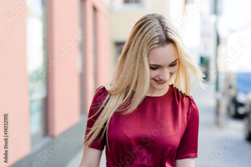 Blonde Frau in rotem Kleid geht in Innenstadt einkaufen