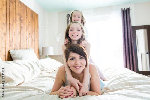 Mother and two children in the bedroom on the bed photo