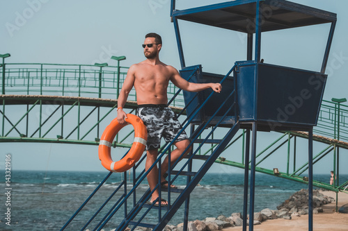 bearded lifeguard or muscular man with orange ring buoy