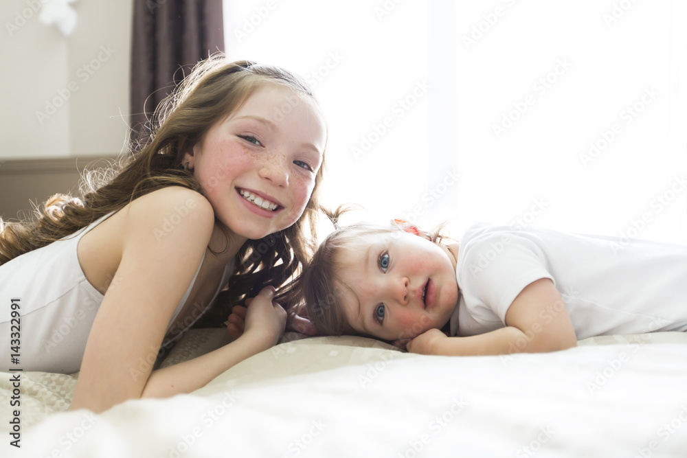 Little sister Toddler kid on bed having fun Little sister Toddler kid on bed having fun