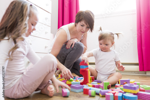 Child girl together with mother and sister playing educational toys