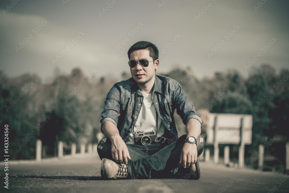 Young man tourist sitting and taking photos with vintage camera.