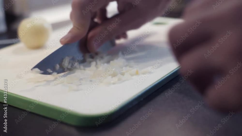 Hands of young man cutting onion at kitchen. Young man preparing vegetable food Hands of young man cutting onion at kitchen. Young man preparing vegetable food