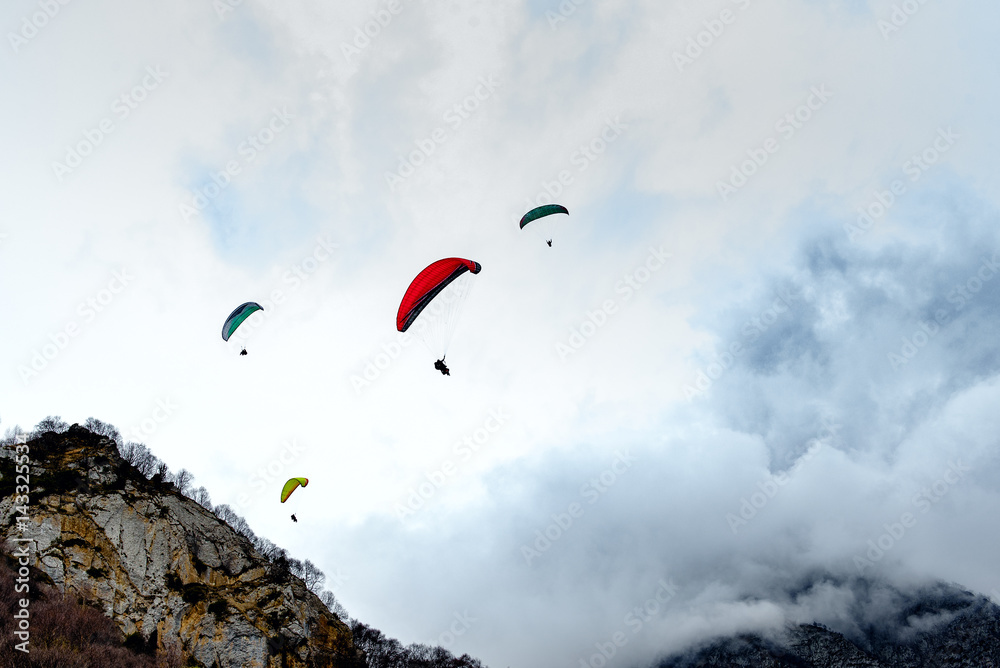 Flying paraglider in the clouds on a background of mountains. Flying paraglider in the clouds on a background of mountains.