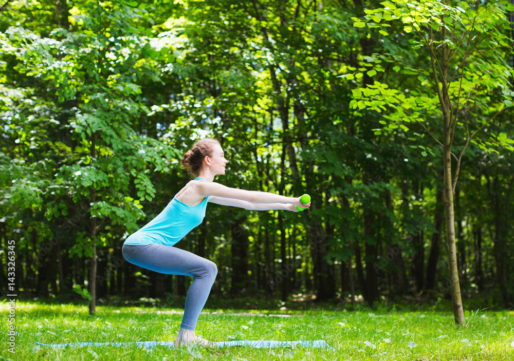 Young slim girl doing exercises outdoors.