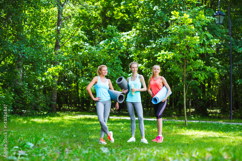 Fitness female group in park on a sunny day. Workout outdoors.
