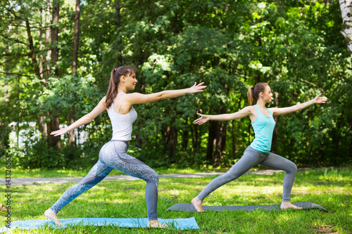 Female friends working out and doing yoga outdoors.