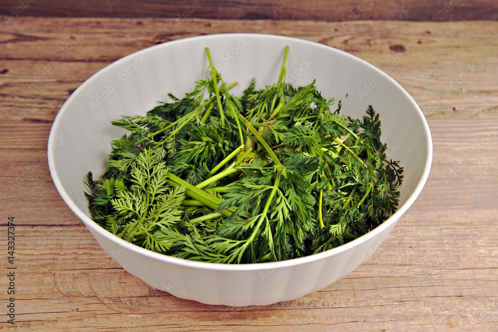 Bio waste-carrot tops in a white plastic bowl Bio waste-carrot tops in a white plastic bowl